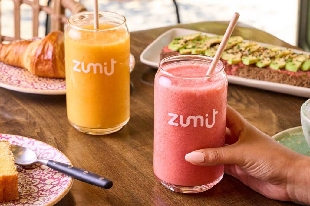 Smoothie natural de mango, piña y papaya en una mesa de madera con un desayuno